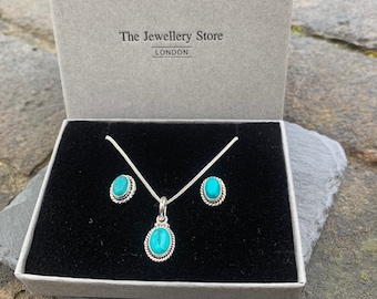 May include: A turquoise and silver necklace and earrings set in a gray box. The box has the text "The Jewellery Store LONDON" on the lid.