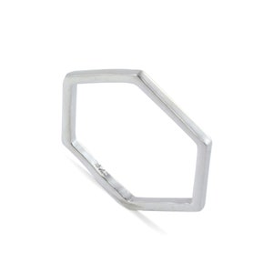 May include: A silver-colored ring with a geometric, pentagon-like shape. The ring is made of a shiny metal and has a minimalist design. The ring is shown on a white background.