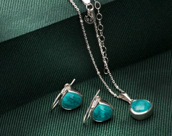 May include: A silver necklace and matching earrings with turquoise teardrop-shaped stones. The necklace has a delicate chain with a small bead detail.