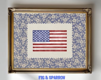 May include: Framed artwork featuring the American flag. The flag is red, white, and blue, with stars and stripes. The flag is set against a floral patterned background in a gold-colored frame. The text "FIG & SPARROW Eclectic Art for Eclectic Souls" is at the bottom.