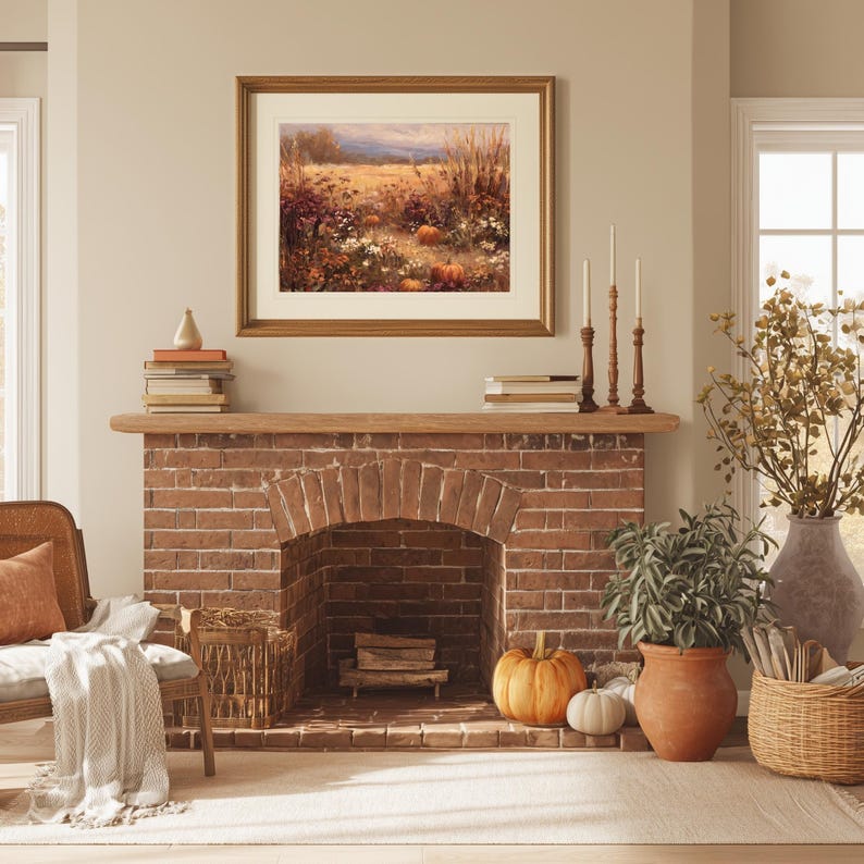 May include: A cozy living room scene featuring a brick fireplace with a wooden mantel. A framed landscape painting hangs above the fireplace. Pumpkins and candles decorate the mantel. A wicker chair with an orange pillow and a blanket sits to the left.