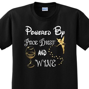 May include: Black t-shirt with white text that reads "Powered by Pixie Dust and Wine". The text is surrounded by gold glitter and a gold fairy with a glass of wine.
