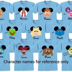 May include: Ten light blue t-shirts with different Muppet characters on them. Each shirt has a Mickey Mouse ear design with the character's face in the center. The shirts are labeled with names like "Ben", "Heather", "Robert", and "Susan".