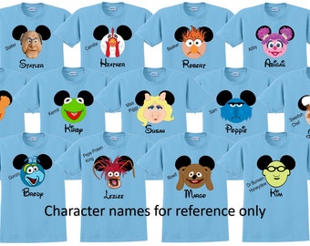 May include: Ten light blue t-shirts with different Muppet characters on them. Each shirt has a Mickey Mouse ear design with the character's face in the center. The shirts are labeled with names like "Ben", "Heather", "Robert", and "Susan".