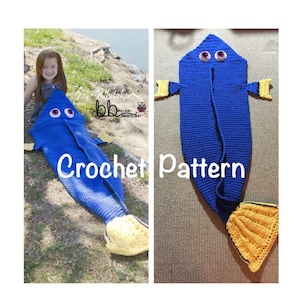May include: Crochet pattern for a blue and yellow Dory fish blanket with a hood. The blanket is laid out flat and a child is wearing the blanket in the background.