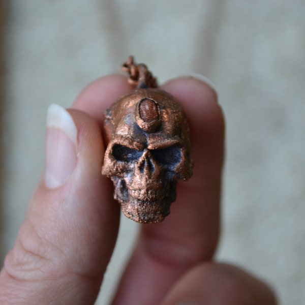 Small Skull with inlaid Burnt Orange Sparkly Goldstone Cabochon Set in Electroformed Copper on a Long Antique Copper Plated Necklace