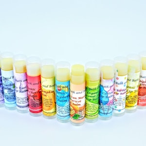 May include: A collection of 16 colorful lip balms in tubes, each with a different flavor and design. The lip balms are arranged in a semi-circle on a white background. The flavors include Coconut, Grape, Blueberry, Earl Grey, Cherry, Pumpkin, Raspberry, Apricot, Cotton Candy, Birthday Cake, Watermelon, Strawberry, and Vanilla.