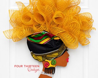May include: A decorative wall hanging featuring a profile silhouette of a person with brown skin, bright pink lips, and a white beaded necklace. The head is adorned with a black headwrap and a large, voluminous yellow mesh floral arrangement.