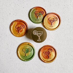 May include: Six round wax seals with a gold, orange, and green ombre design. Each seal features a line drawing of a cocktail glass with a lime wedge.