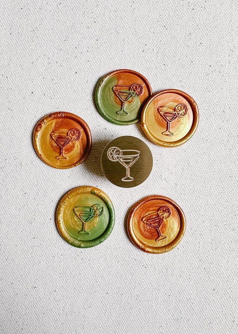 May include: Six round wax seals with a gold, orange, and green ombre design. Each seal features a line drawing of a cocktail glass with a lime wedge.