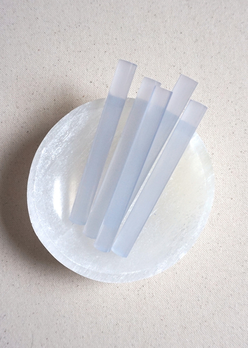 May include: Five translucent blue glue sticks in a white selenite bowl.