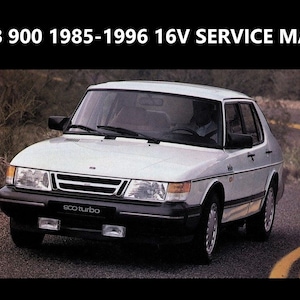 May include: A white Saab 900 Turbo car with black trim and a black grille. The car is driving on a paved road with yellow lines.