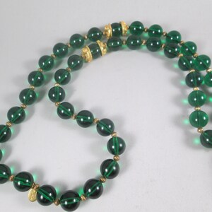 Pu&ograve; includere: Una collana di perline di vetro verde con dettagli dorati. La collana &egrave; composta da perline rotonde con un design sfaccettato. Le perline sono infilate su una catena dorata.