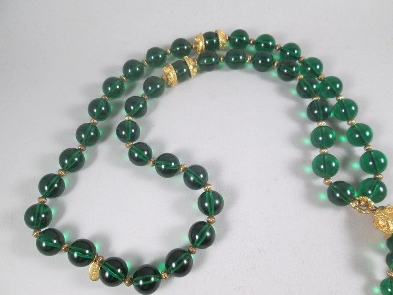 Pu&ograve; includere: Una collana di perline di vetro verde con dettagli dorati. La collana &egrave; composta da perline rotonde con un design sfaccettato. Le perline sono infilate su una catena dorata.