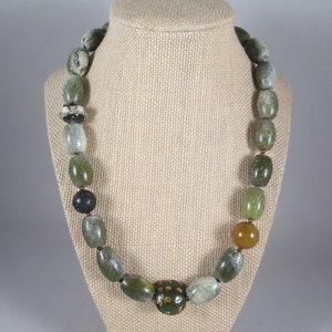 May include: A green and brown stone bead necklace with a variety of beads, including a large green bead with a geometric pattern.