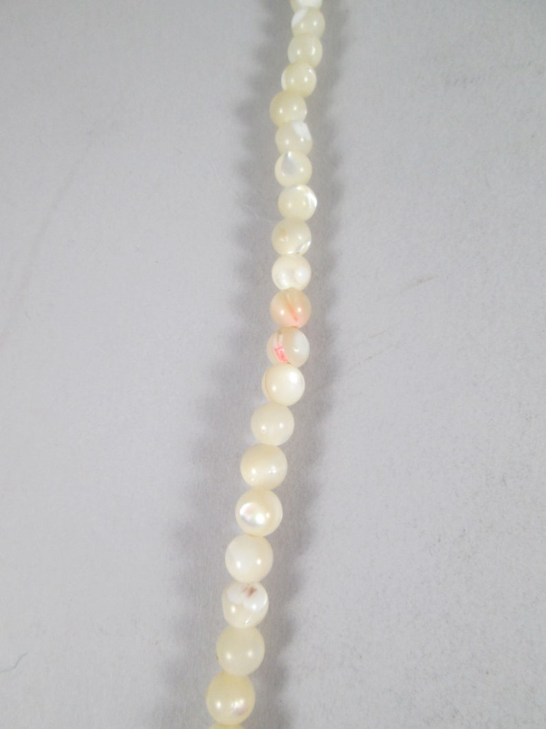 May include: A strand of white pearl beads with iridescent shimmer.
