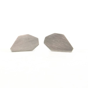 May include: A pair of silver geometric stud earrings. The earrings are shaped like a diamond with a brushed finish.