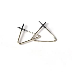 May include: A pair of silver triangle earrings with black accents. The earrings are simple and modern in design.