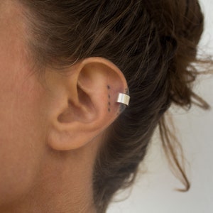 a smouth fitted ear cuff of Silver 925, placed around the earlobe. A light weight ear cuff with a matt finish. The lenght is 5 cm.