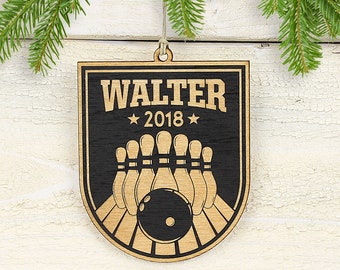 May include: Wooden bowling-themed Christmas ornament with the name "WALTER" and the year "2018" engraved. The ornament features a black shield design with a bowling ball and pins, and is hanging from a natural twine string.