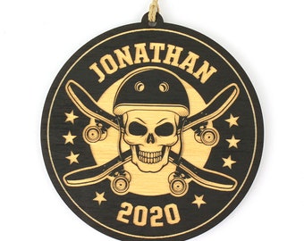 May include: Round wooden ornament with a black border and a light wood center. The design features a skull wearing a helmet, crossed skateboards, stars, the name "JONATHAN", and the year "2020". A string is attached for hanging.