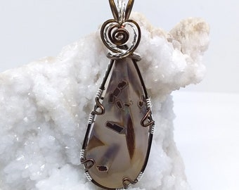 May include: A teardrop-shaped pendant with a brown and white agate stone wrapped in silver wire. The pendant has a silver heart-shaped bail with a copper wire swirl.