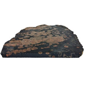 May include: A close-up of a dark gray and black stone with copper-colored spots. The stone has a rough, natural texture.