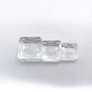 Könnte beinhalten: Drei transparente Glas-Präsentationsständer in verschiedenen Größen, perfekt für die Präsentation kleiner Gegenstände wie Schmuck oder Kristalle.