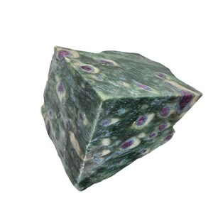 May include: A large, rough, green and white rock with pink and blue inclusions. The rock has a mottled appearance and is irregularly shaped.