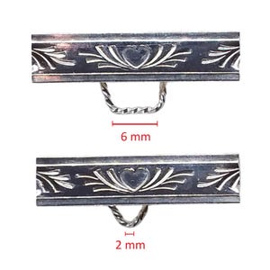 May include: Two silver-toned metal clasps with decorative floral and heart patterns. Each clasp has a twisted loop. The top clasp is 6 mm wide, and the bottom clasp is 2 mm wide. The clasps are shown against a white background.
