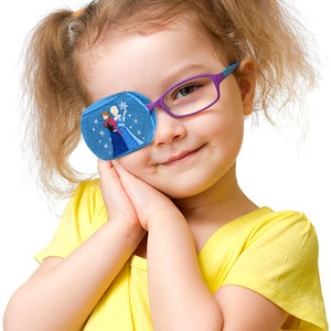 May include: A blue eye patch with an embroidered image of Elsa and Anna from the movie Frozen. The eye patch is being worn by a young girl with blonde hair and purple glasses.
