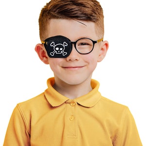 May include: A young boy wearing a yellow polo shirt and round glasses with a black eye patch with a white skull and crossbones design.