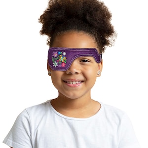May include: A purple eye patch with a colorful floral embroidery design. The patch is worn over the right eye of a young person with curly hair.