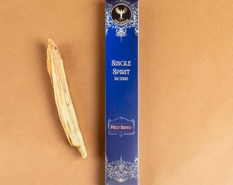 May include: A blue box of "Single Spirit Incense" with "Palo Santo" text, next to a piece of Palo Santo wood. The box has a decorative white design and a logo at the top. The background is a solid tan colour.