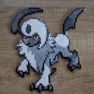 Peut inclure: Une figurine en pixel art d'une créature, principalement dans les tons de gris, blanc et noir, avec des accents rouges. La figurine est faite de petites perles de plastique fusionnées. La créature a une forme distinctive avec des éléments en forme d'ailes et une pose dynamique.