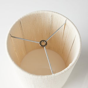 May include: A white lampshade made of woven rope with a metal frame.