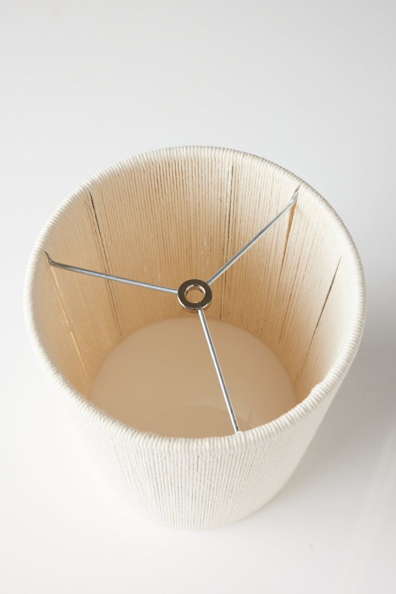 May include: A white lampshade made of woven rope with a metal frame.