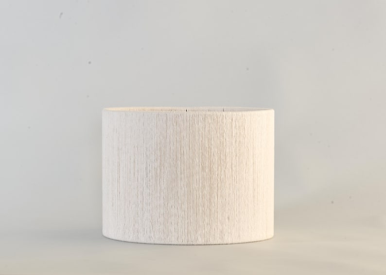 Puede incluir: Pantalla de l&aacute;mpara cil&iacute;ndrica con superficie texturizada blanquecina. La pantalla presenta un patr&oacute;n lineal vertical y est&aacute; dise&ntilde;ada para colocarse sobre una base de l&aacute;mpara. El color neutro y el dise&ntilde;o sencillo la hacen adecuada para varios estilos de interior.