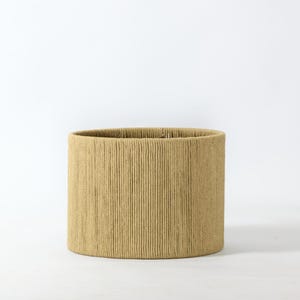 Puede incluir: Una pantalla de l&aacute;mpara cil&iacute;ndrica con un patr&oacute;n texturizado de l&iacute;neas verticales. La pantalla es de color beige claro y tiene un dise&ntilde;o simple y minimalista. La pantalla es adecuada para una l&aacute;mpara de mesa o de pie.