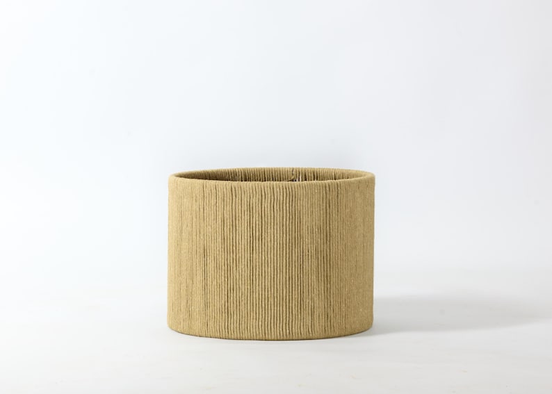 Puede incluir: Una pantalla de l&aacute;mpara cil&iacute;ndrica con un patr&oacute;n texturizado de l&iacute;neas verticales. La pantalla es de color beige claro y tiene un dise&ntilde;o simple y minimalista. La pantalla es adecuada para una l&aacute;mpara de mesa o de pie.