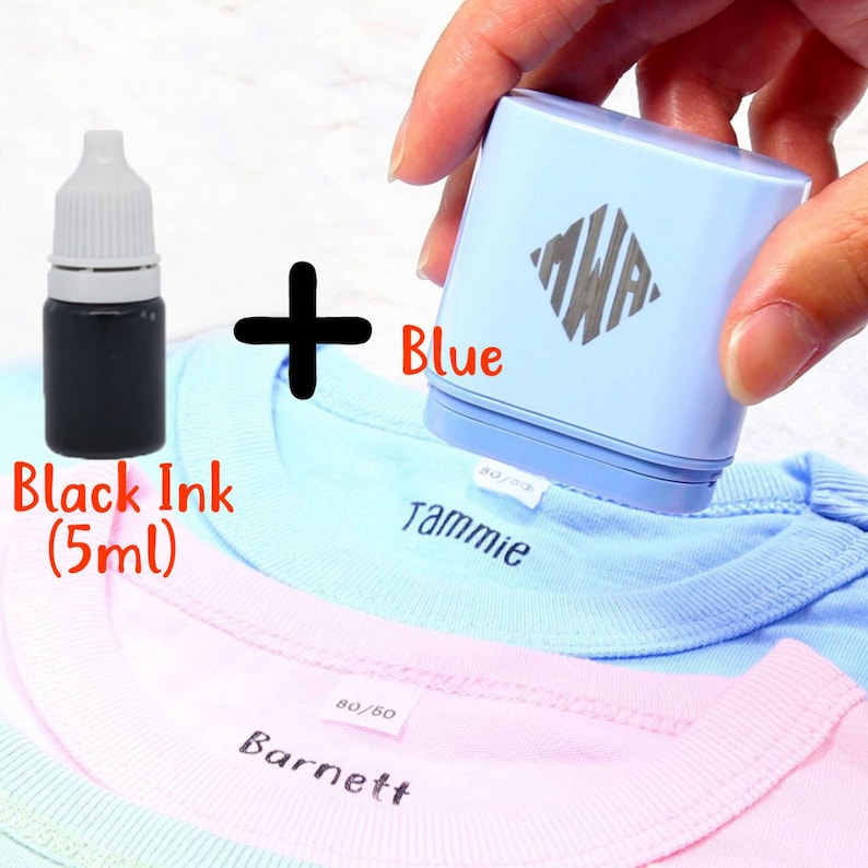 May include: A blue fabric stamper with the initials "MWA" printed on it. The stamper is being used to stamp the name "Tammie" on a light blue t-shirt. A small bottle of black ink is included. The ink bottle says "Black Ink (5ml)".