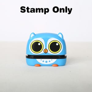 May include: A blue and yellow owl-shaped stamp with large eyes and a black beak. The stamp is made of plastic and has a white belly with black dots.