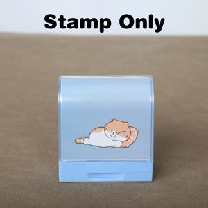 May include: A light blue plastic stamp featuring a cartoon cat sleeping on a pillow. The stamp reads "Stamp Only" at the top.