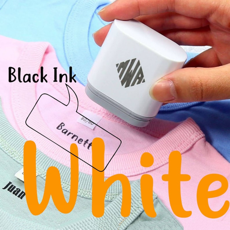 May include: A white handheld fabric label maker with a black diamond logo and the text "MWA" inside the diamond. The label maker is being used to label a pink shirt with the text "Barnett" in black ink. The text "Black Ink" is written in a speech bubble above the label maker. The text "White" is written in orange below the shirt.