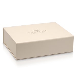Puede incluir: Una caja de color crema con el texto "Camellia for that yes moment" impreso en la parte superior.