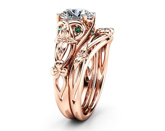 Pode incluir: Um anel de noivado em ouro rosa com uma grande pedra central redonda e detalhes florais intrincados. A banda é adornada com pedras menores e folhas delicadas.