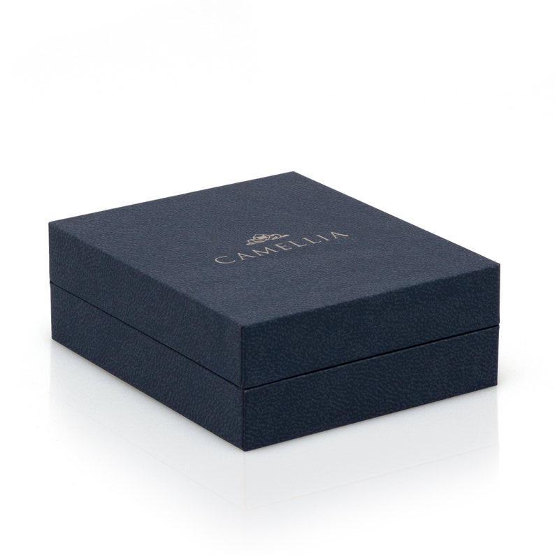 Puede incluir: Una caja azul oscuro con la palabra "CAMELLIA" impresa en letras doradas en la parte superior.