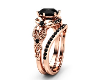 May include: Rose gold engagement ring set with a black diamond center stone and black diamond accents. The ring features a floral design with intricate details.