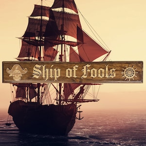 May include: A wooden sign with the text "Ship of Fools" in a decorative font. The sign is brown with a skull and crossbones on the left and a ship's wheel on the right. The sign is in front of a large ship with red sails.