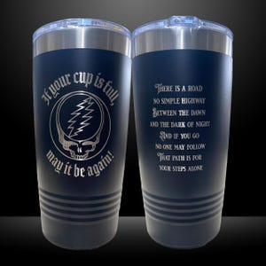 May include: Navy blue insulated tumbler with a silver lid. One side features a skull and lightning bolt design with the text "If your cup is full, may it be again!". The other side has a poem.